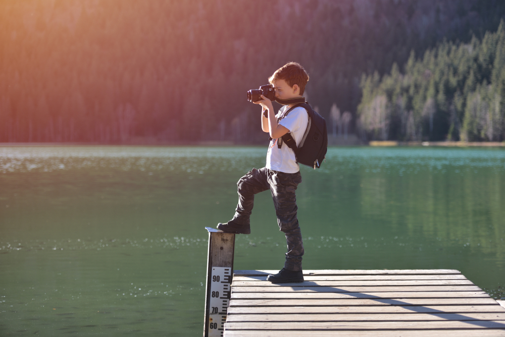 Child taking landscape photos from a dock