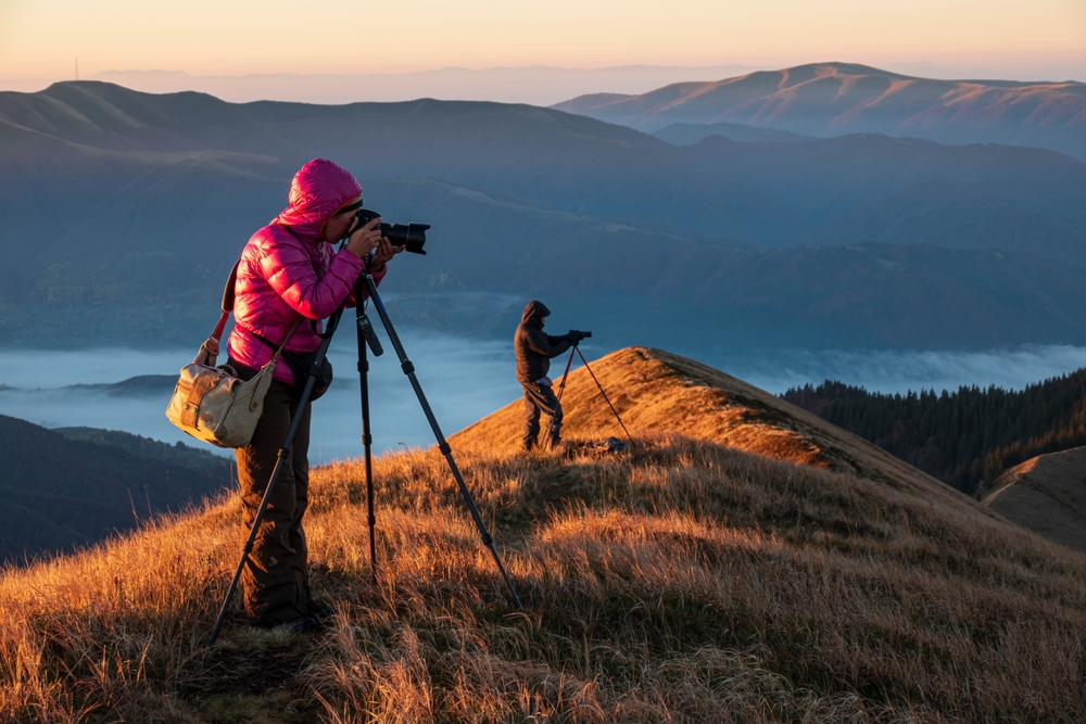 Landscape photographers with the tripods on the mountain top at sunrise