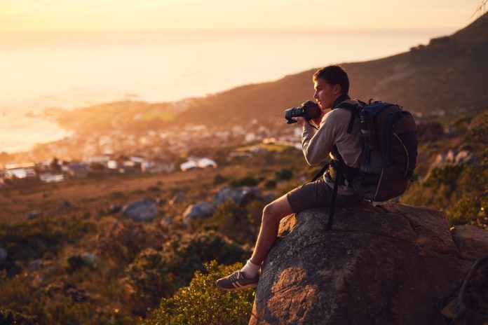 Man sitting on a rock taking photos at golden hour