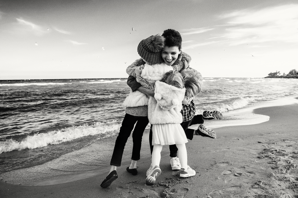mother with three children hugging at the beach