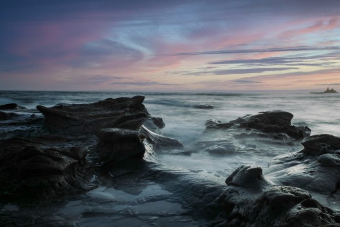 ocean waves crashing on rocks during blue hour