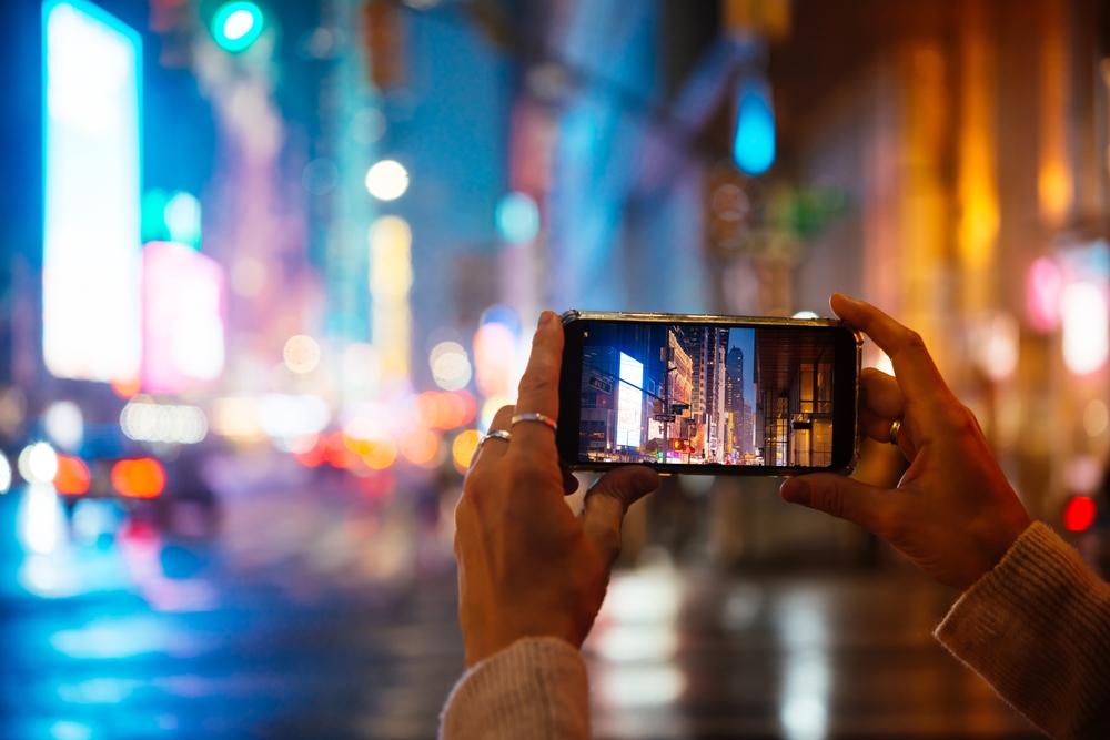 person takes a photo of lights in Manhattan