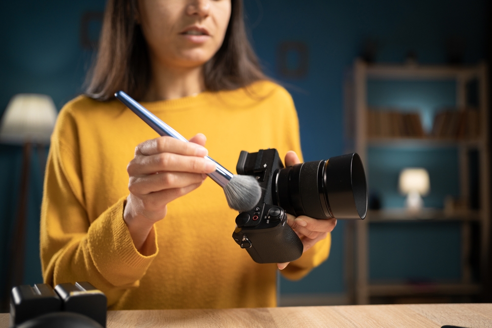 photographer cleaning dust from camera using brush