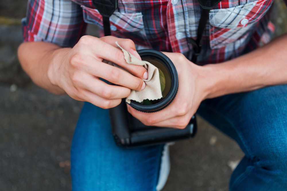 Photographer cleaning lens with a cloth