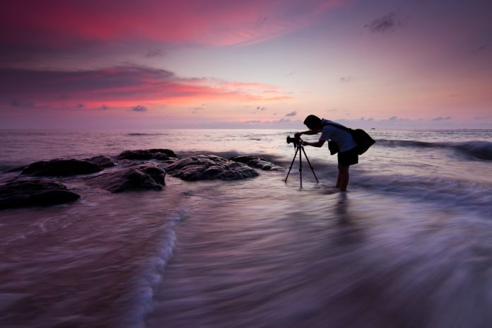 photographer setting up camera on tripod at sunset