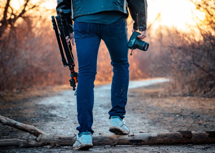 Photographer walking on a trail with his camera and tripod