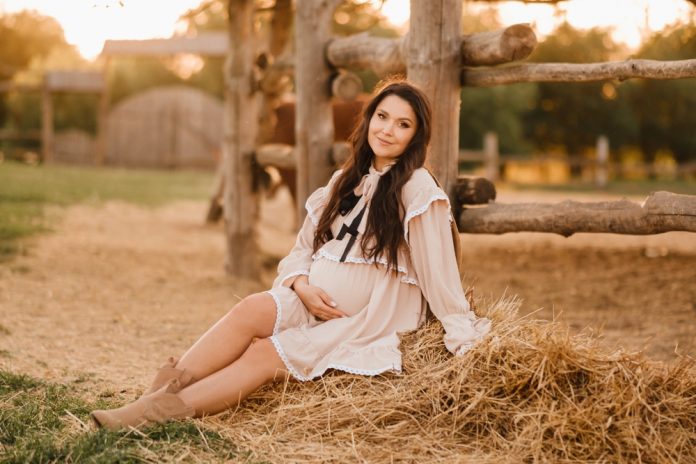 pregnant woman sitting on haybales