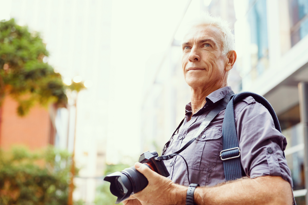 Senior man with camera in city