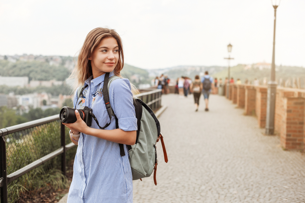 Woman holding a camera and wearing a backpack