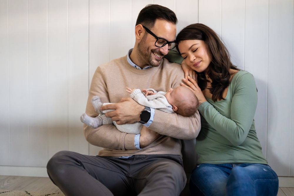 young happy man and woman holding newborn baby
